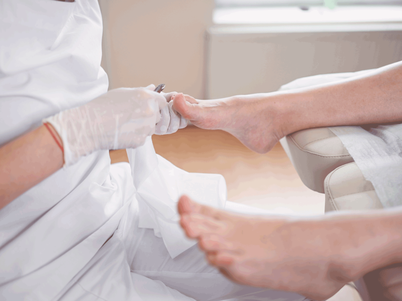 Professional medical pedicure procedure close up using nail clippers instrument. Patient visiting chiropodist podiatrist. Foot treatment in SPA salon. Podiatry clinic. Pedicurist hands white gloves.